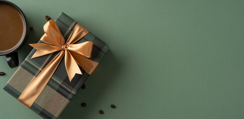 Top view of a striped gift box with golden ribbon next to coffee on green
