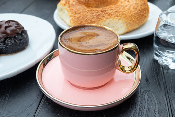 pink cup with black coffee, Turkish bagel with sesame seeds (simit) and a glass of water.Breakfast concept