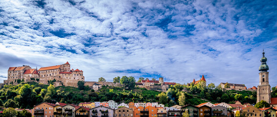 Panoramabild der Stadt Burghausen an der Salzach mit Burganlage unter weiß-blauem Himmel 