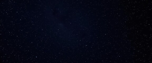 Vast, dark expanse speckled with distant, faint stars, cosmic dust, astrophotography, distant stars