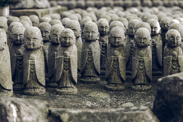 Close-up of small Jizo figures at Hase-dera temple in Kamakura Japan arranged in rows with a...