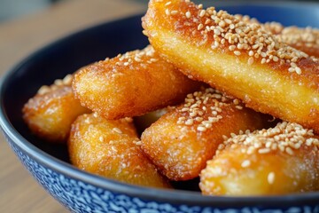 Golden Fried Dough Sticks with Sesame Seeds in a Blue Bowl