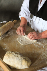 Hands roll rolled out dough together