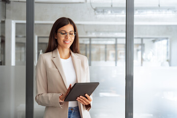 Latin hispanic professional business woman working on computer at office workplace. Young businesswoman manager using pc tablet for sales management, financial operations, looking at digital gadget
