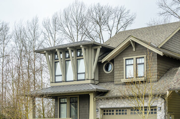 Top of luxury house with shingle roof, red and yellow trees and nice windows in Summer in...