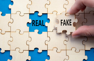 Real or Fake symbol. Concept word Real or Fake on wooden blocks. Businessman hand. Beautiful blue...
