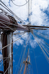 Obraz premium A sailboat with a mast and a blue sky in the background. The sail is full and the mast is tall