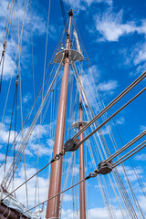 Obraz premium A tall mast with a blue sky in the background. The mast is covered in ropes and has a few people on it