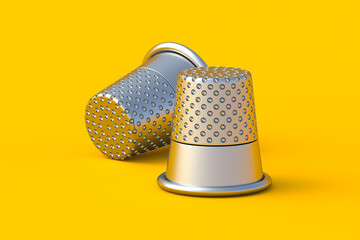 Two sewing thimbles on yellow background. Dressmaking tool. Tailor's protection. Atelier equipment. 3d render