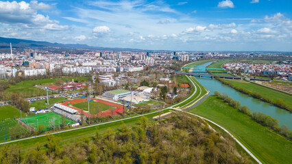 Fototapeta premium Aerial drone view of Park Jarun in Zagreb, showcasing stunning blue water, lush greenery, and the nearby Sava River Park features excellent bicycle roads, perfect for cycling and outdoor activities