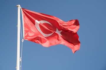 A red Turkish flag waving in the sky.