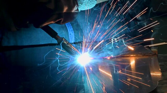 Factory worker joining metal parts using gas welding
