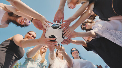 Friends celebrating their graduation by raising a soccer ball in the air