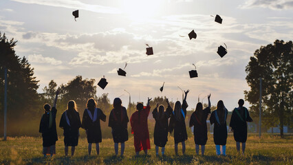 Students in academic gowns toss graduation caps into the air at sunset, celebrating their academic accomplishments as a group