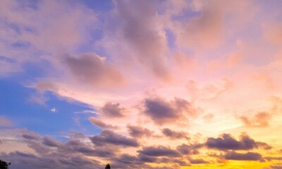 Obraz premium Stunning sunrise sky with soft clouds in shades of blue, yellow, and white. A cinematic natural background perfect for summer scenes, nature designs, and atmospheric visuals.