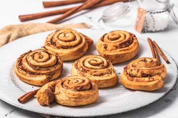 Homemade cinnamon rolls on white plate on white marble background