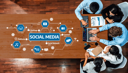 A diverse team collaborates in a modern office setting, analyzing social media strategies through infographics and data analytics on laptops and digital platforms. Amity