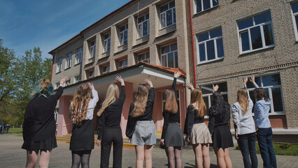 Group of students waving goodbye to their school on the last day, celebrating the end of the academic year