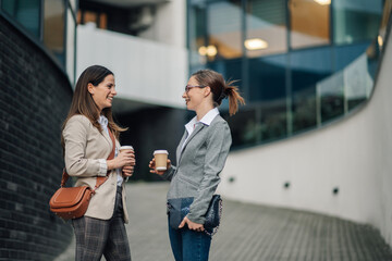 Businesswomen drinking coffee and chatting during a break outside office building