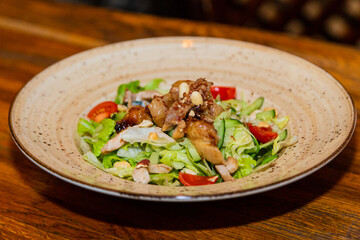 Salad with meat and nuts on a plate on a wooden table. Close-up