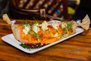 Baked fresh red fish on papyrus in a plate with cheese and lemon