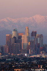 Obraz premium Los Angeles skyline with snow covered mountains in the distance at sunset