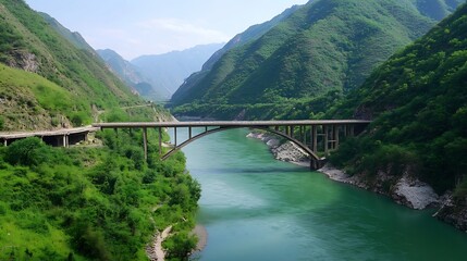 Fototapeta premium A breathtaking view of a river flowing through green mountains with a bridge crossing over : Generative AI