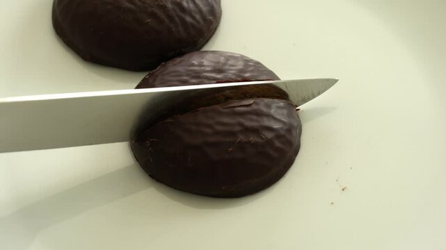 Cutting chocolate coated gingerbread (Lebkuchen) on a white plate and see what is inside. 