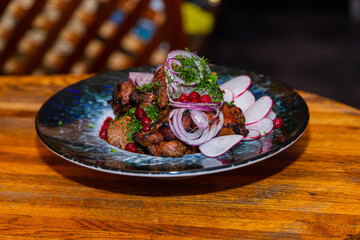 Grilled meat with baked vegetables on a plate on a wooden table in a restaurant.Tasty appetizing food
