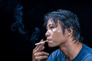 A close appearance of Asian men smokes with a black background for photocopying space.