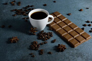 Cup of espresso and chocolate with coffee beans on the side.