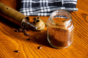 Coffee beans on a wooden table with a manual coffee grinder