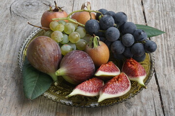 Assorted Fresh Fruits Including Grapes, Figs, and Medlar on a Wooden Plate
