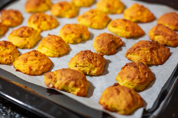 Bright orange Pumpkin cookies baked in the oven on an iron baking sheet on baking paper