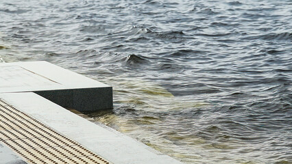 Edge of the stone embankment and the high water in the river.