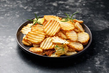Homemade Crinkle Cut French Fries on plate with rosemary. Crispy potato fries snack,