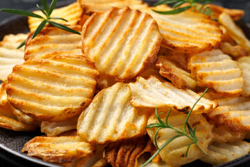 Homemade Crinkle Cut French Fries on plate with rosemary. Crispy potato fries snack,