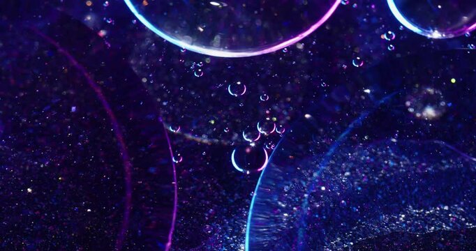 Light bubbles. Abstract molecule. Defocused blue purple neon colorful oil droplet sequins round liquid circling on acrylic background.