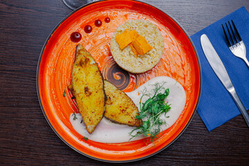 Grilled fresh red fish lies on a plate along with a side dish and sauce. delicious fresh wholesome food in the restaurant. view from above