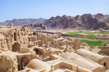 Panorama of remains of buildings in village of Kharanaq, surrounded by mountains, Yazd Province, Iran. Old town was abandoned by locals, but nowadays it  become tourist attraction