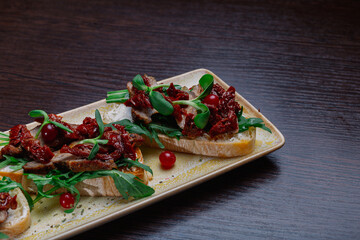 Appetizing sandwiches with meat, greens and berries on a plate.Snack for alcoholic drinks. edge of the plate