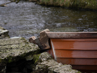 An abandoned boat partially submerged in a calm lake,creating a tranquil and moody atmosphere in a rural setting