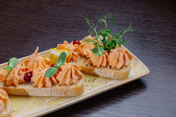 White bread sandwiches with fish cream and herbs on a white plate. appetizer for wine.beautiful design of the dish