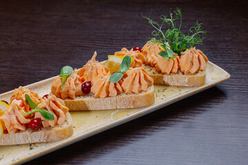 White bread sandwiches with fish cream and herbs on a white plate. appetizer for wine. beautiful design of the dish. exclusive