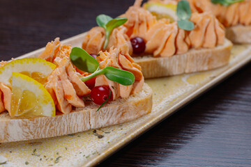White bread sandwiches with fish cream and herbs on a white plate. appetizer for wine. beautiful design of the dish. new trend. appetizing view of food close-up plan