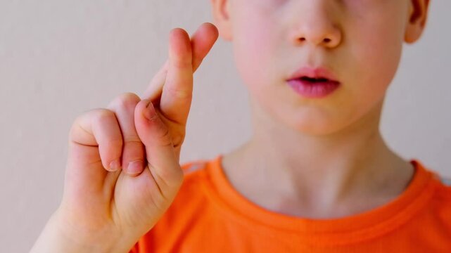 child's crossed fingers for luck, 9-year-old boy making motivational Symbolism and Gestures of Believing in Luck symbolizing hope, support, optimism concept emotional development, encouragement symbol