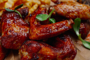 Appetizing fried wings with french fries sauce and beer on a wooden board. wings large
