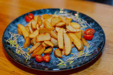 Rustic fried potatoes with fresh tomatoes on a beautiful plate on a wooden table. big frame