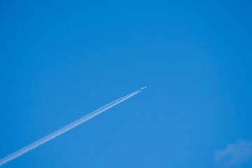a twin engined jet liner aircraft in deep blue sky, contrails vapour trails