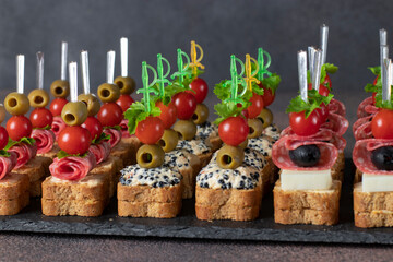 Assortment of canapes with cherry tomatoes, sausage, cheese, olives and seaweed caviar on slate plate